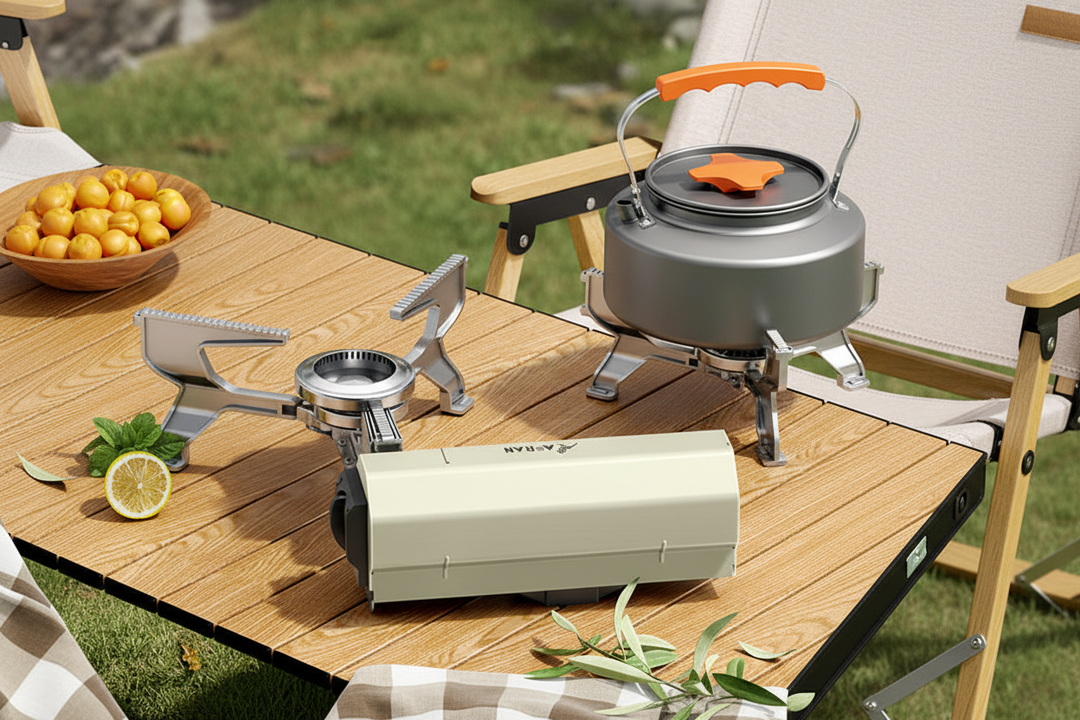 Cream white portable folding cassette camping stove with silver spider-leg burner head and gray aluminum 1.6L kettle on wooden folding table