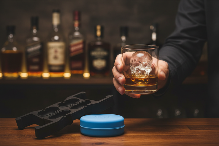 Silicone skull ice mold - hand holding whiskey glass with crystal-clear skull ice cube at home bar
