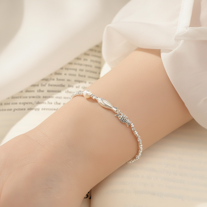 Sterling silver fish pearl bracelet on wrist with book