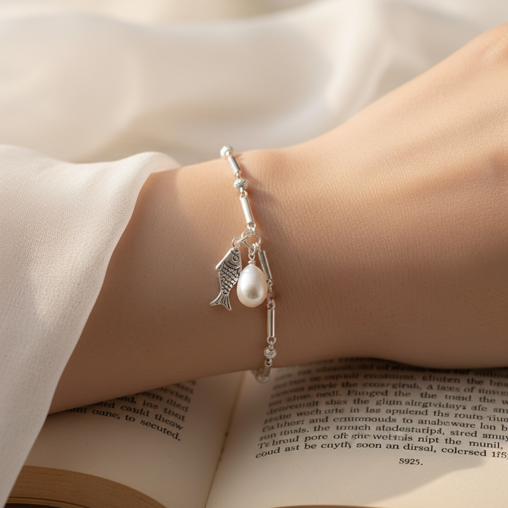 Sterling silver fish pearl bracelet on wrist with chiffon and book